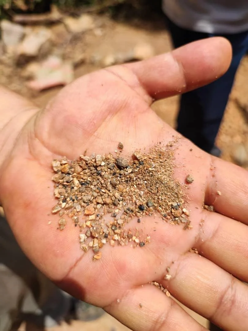 Hand holding mixed alluvial gravel and concentrate