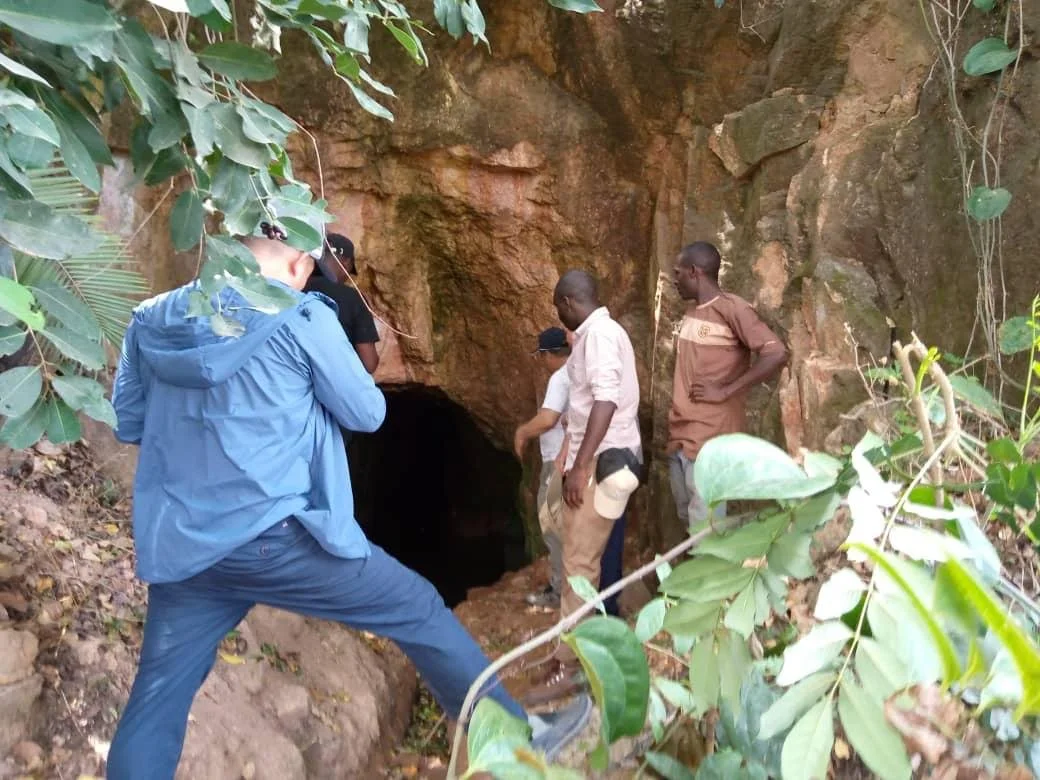 Team inspecting a rock outcrop and opening in dense bush