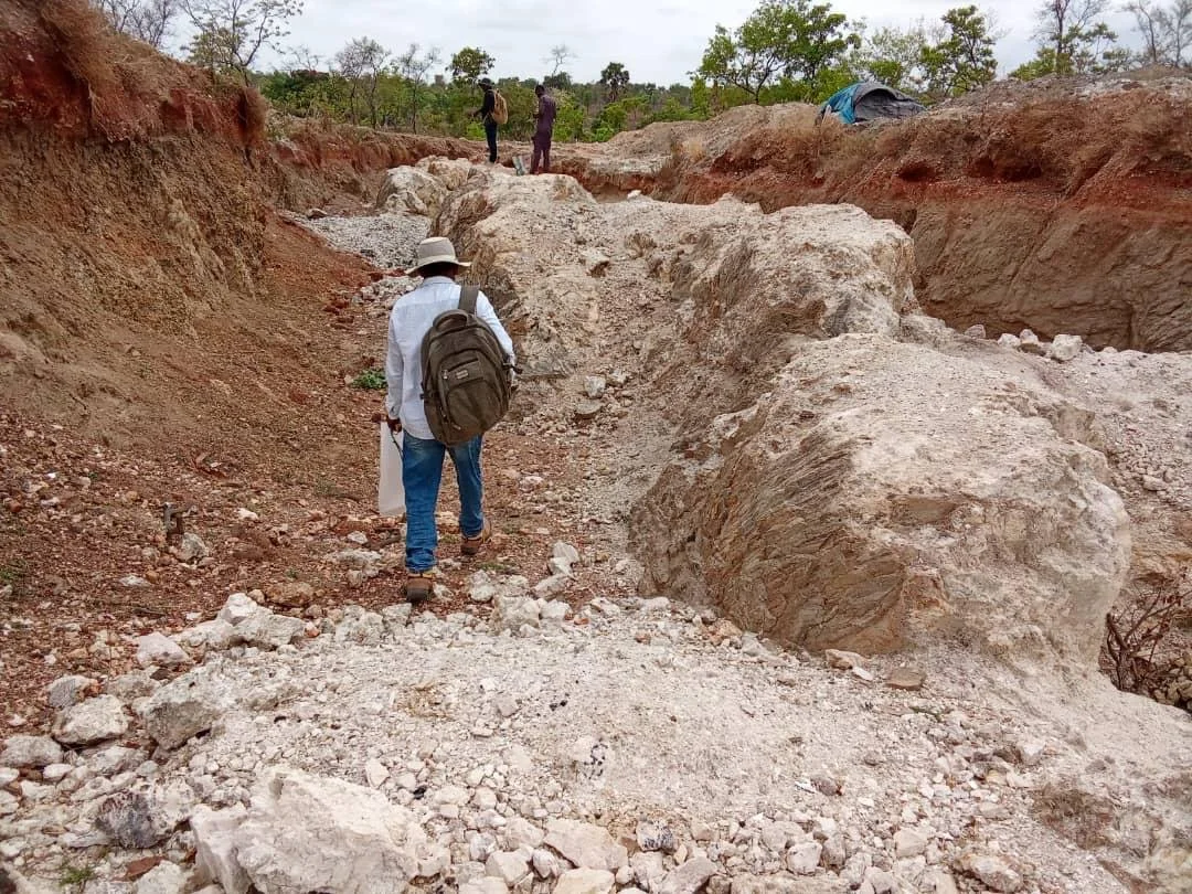 Geologist walking through a trench cut into quartz-rich rock