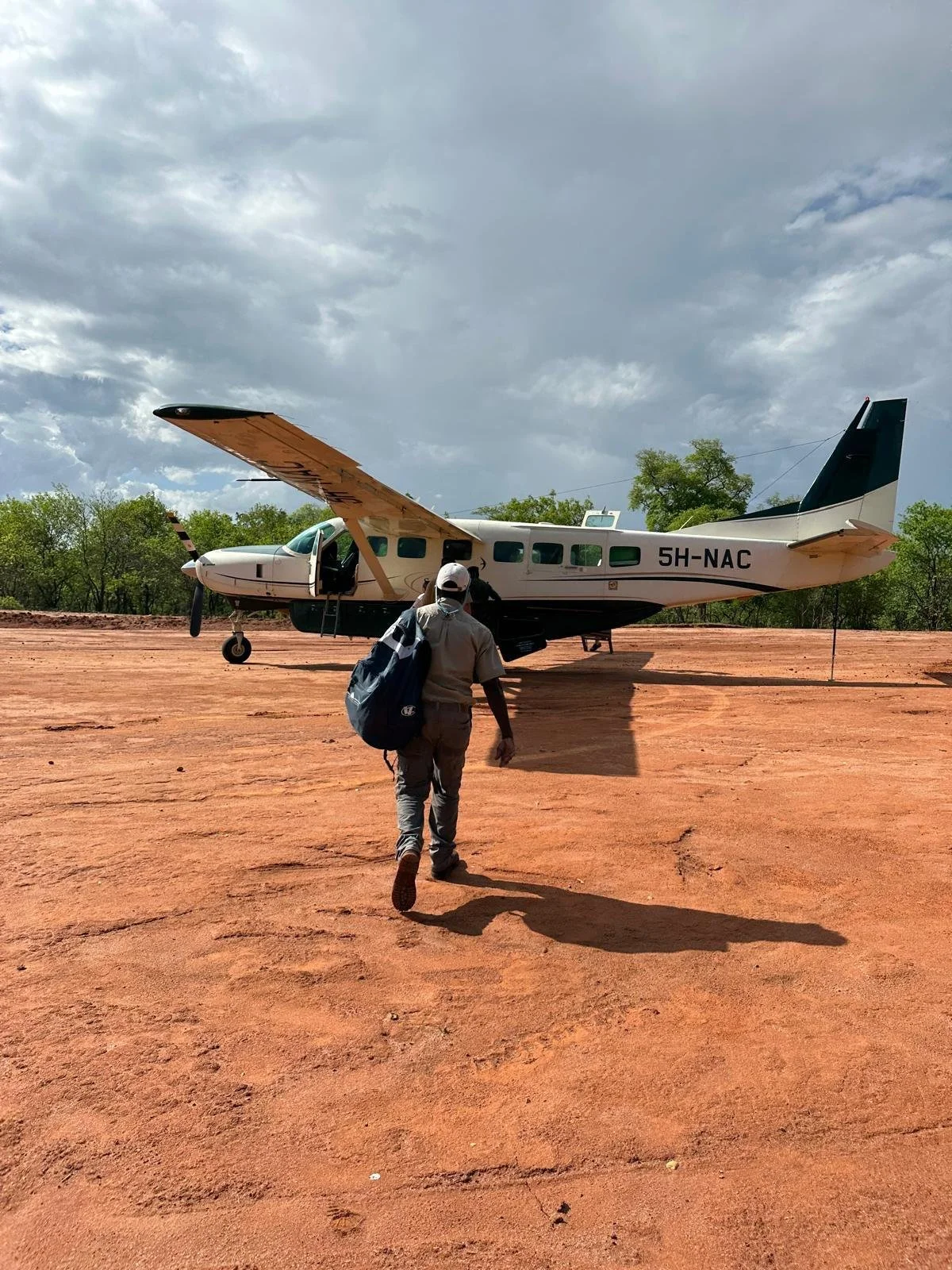 Field geologist walking to a light aircraft on a remote red-dirt airstrip