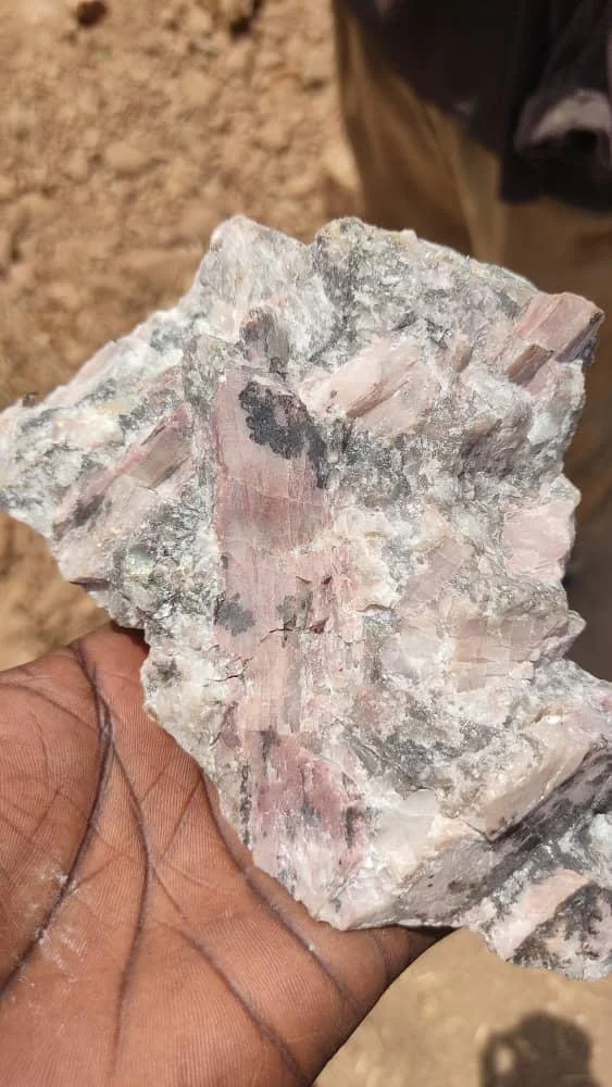 Pink crystalline mineral specimen examined during field exploration